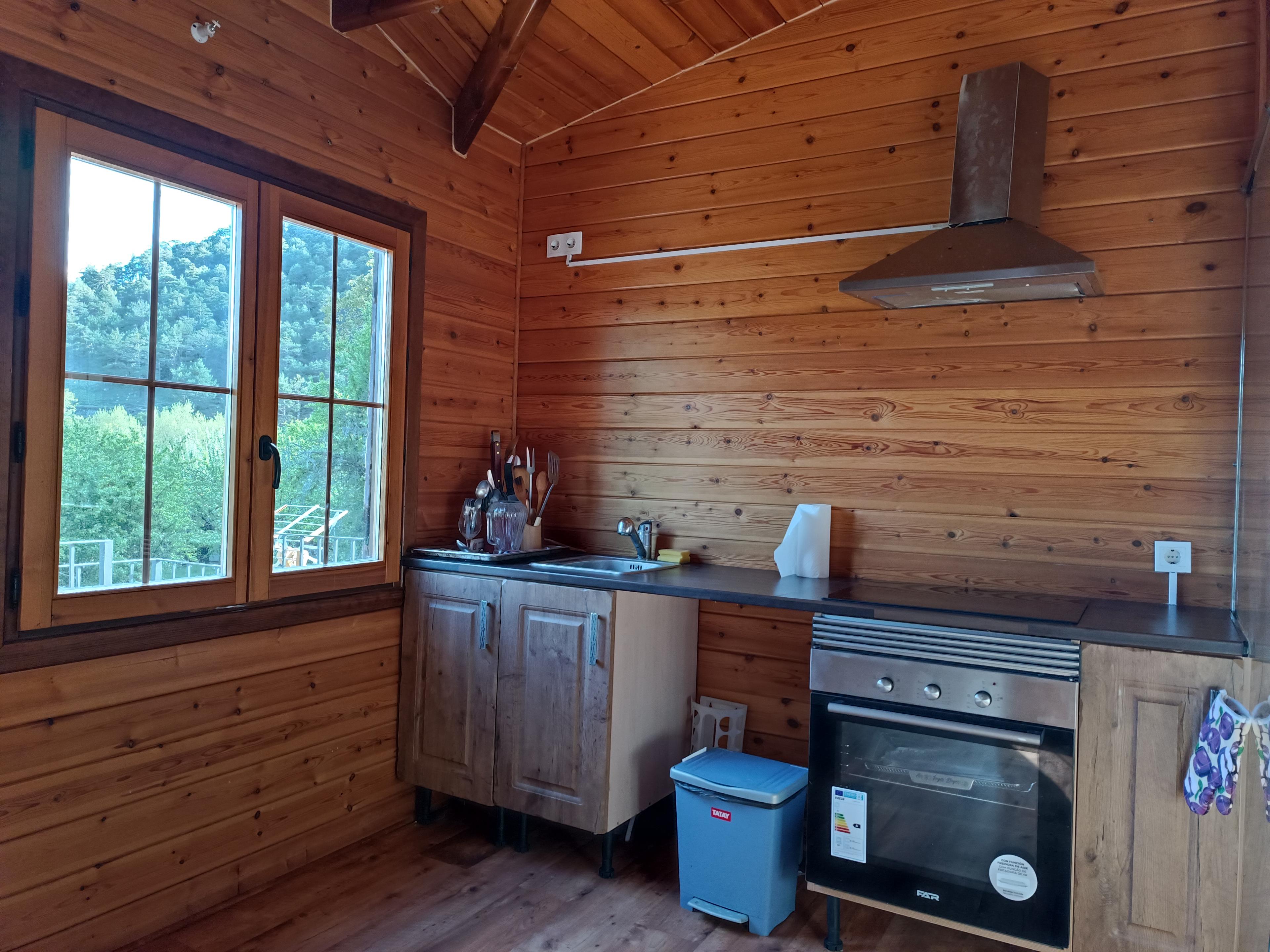 Cocina con encimera, horno, vitrocerámica y ventana hacia la montaña