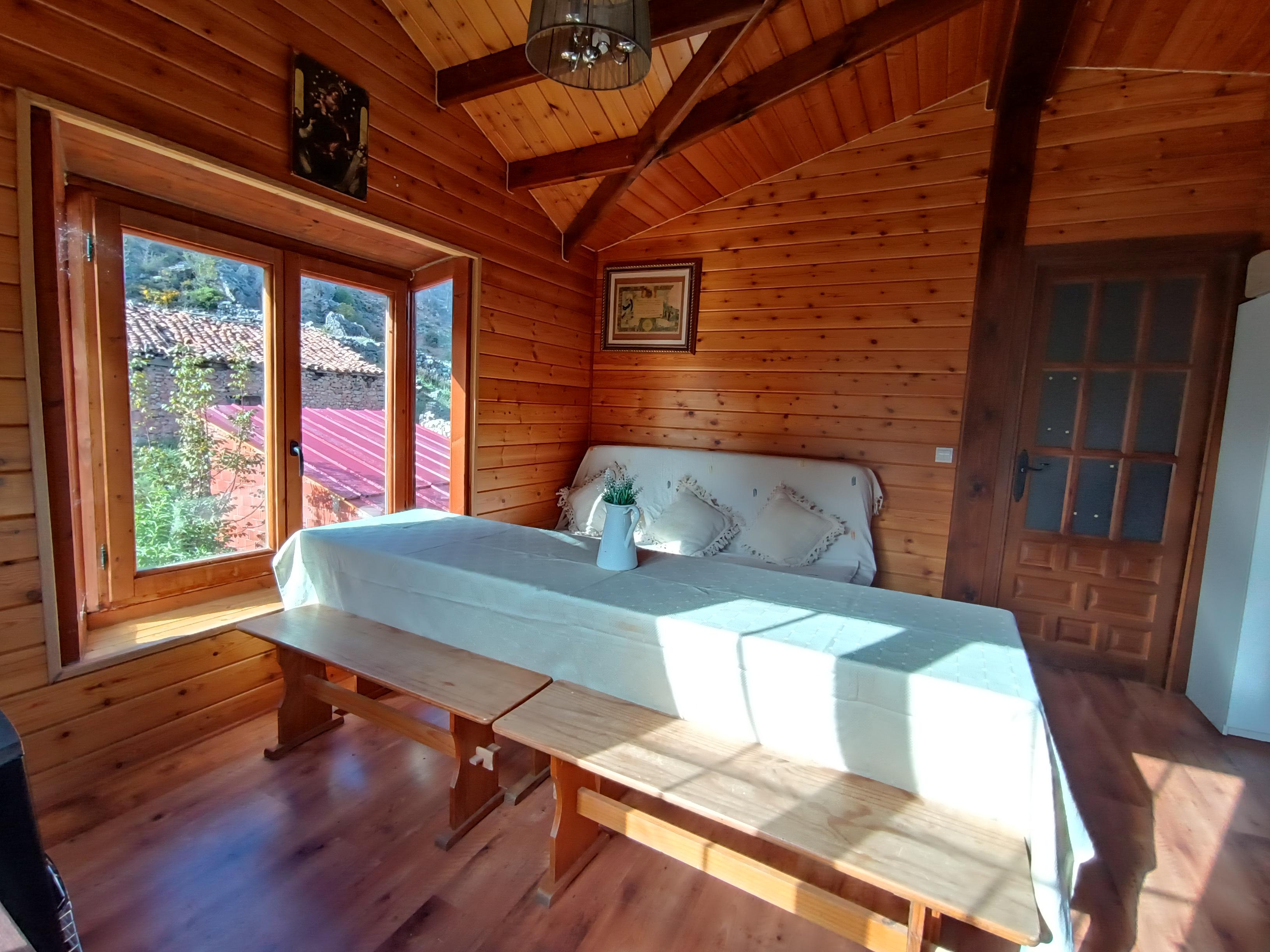 Comedor con mesa larga, bancos de madera y sofá al fondo bañado por el sol