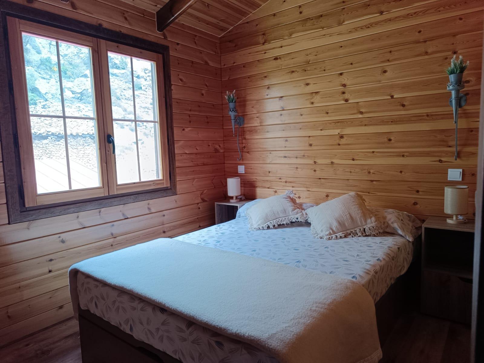 Habitación de los buitres con cama de matrimonio y ventana a la pared rocosa