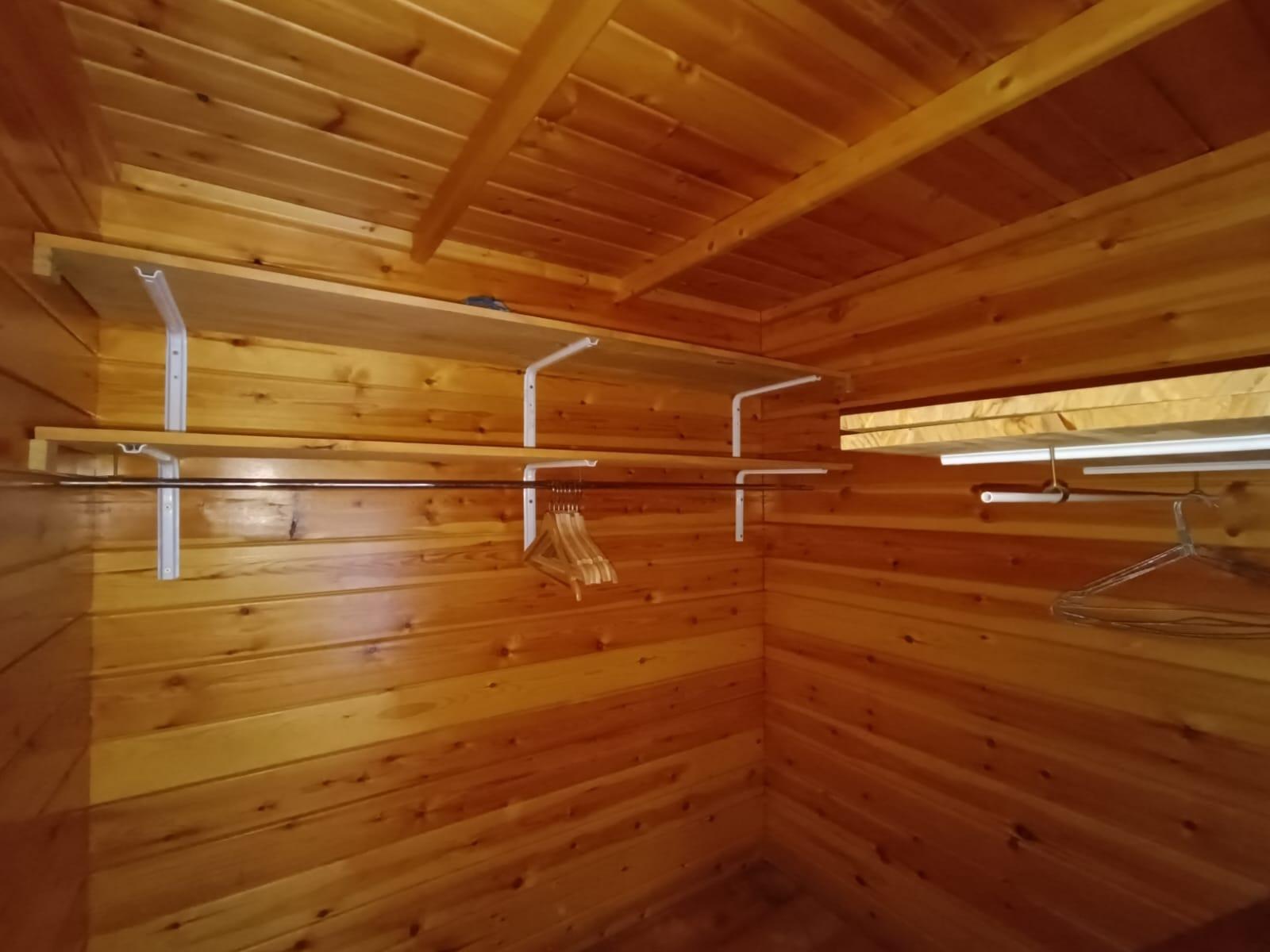 Habitación principal con vestidor de madera, baldas y barra para colgar ropa