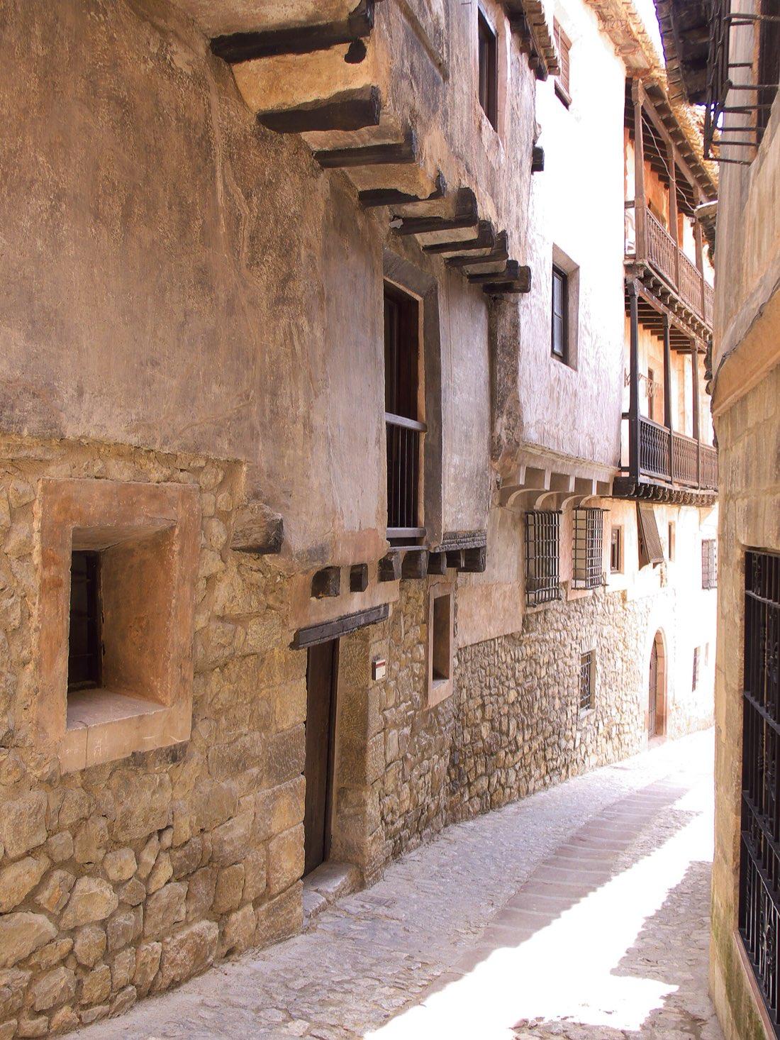 Narrow street in the old town of Albarracín with stone and reddish gypsum walls