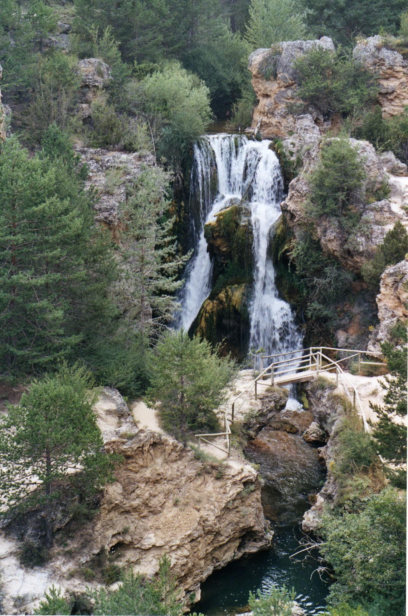 Cascada de Calomarde desde el mirador, con las barandillas de la bajada y la poza