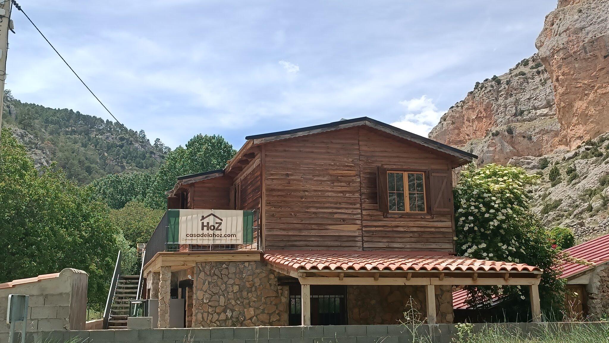 La casa de madera con su porche y balcón, al pie de los riscos del barranco de la Hoz